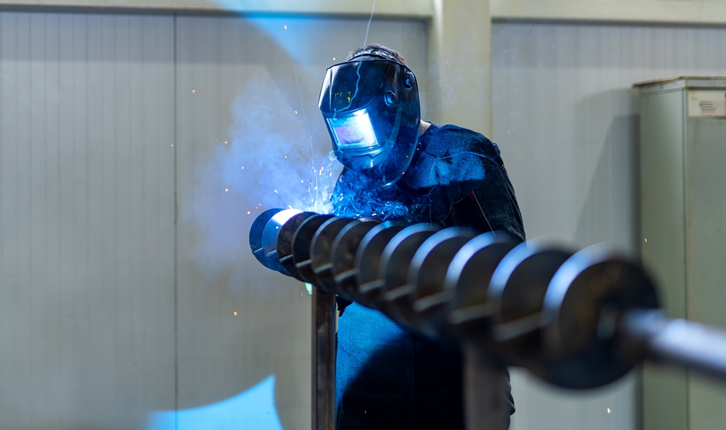 Welding specialist working with protective mask. Factory metal worker welding.